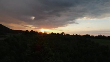 Kırsal kesimdeki güzel dağların üzerinde, destansı, sessiz günbatımının insansız hava aracı görüntüleri. Gökyüzünün bulutlu renkleri. Karışık ormanın ve çayırın karanlık gölgeleri. Dramatik Günbatımı Manzarası