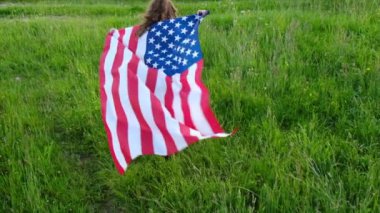 Yaz mevsiminde arka plandaki dağlarda ulusal Amerikan bayrağıyla yeşil alanda koşan küçük anaokulu kızına bakıyorum. Amerikan bayrağı, ülke, vatanseverlik, bağımsızlık anma günü 4 Temmuz