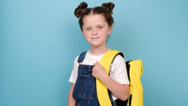 近照可爱的笑容可亲的白俄罗斯小女孩的肖像 小学生背着黄色的背包站在蓝色工作室的背景墙上 正面看着相机 回到学校的概念 — 图库视频影像