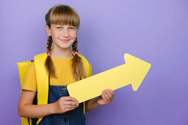 Sonriendo Linda Colegiala Mostrando Lado Con Flecha Amarilla Lleva Mochila — Foto de Stock