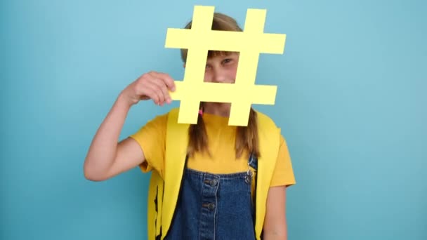 Alegre Colegiala Adorable Con Mochila Amarilla Sosteniendo Gran Símbolo Hashtag — Vídeos de Stock