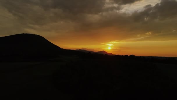 曇りの日に壮大な映画の暗い日没の間に山のピークの空中ビュードローンショット 太陽は夕暮れや夜明けの時間の間に地平線上に沈む 穏やかな自然と屋外のキャンプビブ — ストック動画