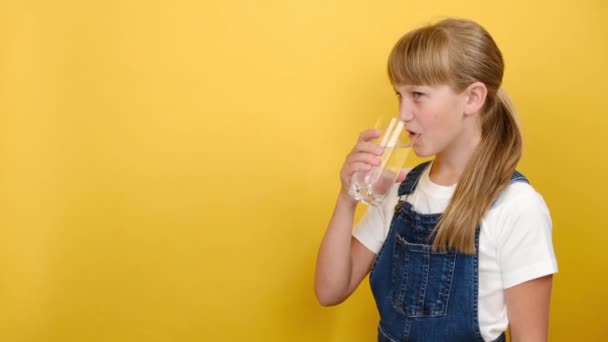 Saludable Chica Linda Escuela Beber Agua Aislado Sobre Fondo Amarillo — Vídeos de Stock