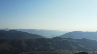 İnsansız hava aracı, ağaçların tepelerinde, tarlaların üzerinde uçuyor. Güzel yaz ya da sonbahar, sakin dağlar, mavi gökyüzü arka planında. Turizm ve seyahat konsepti için park keşfi ve seyahat merkezi