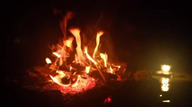 Gece kamp ateşi, nehrin kenarında fener ışığında dinleniyor. Güzel şenlik ateşi, sonbaharda ya da yaz mevsiminde eski odunları yakmak. Aktif yaşam tarzı, seyahat, yürüyüş. Kamp havası ve açık hava yaşam tarzı.