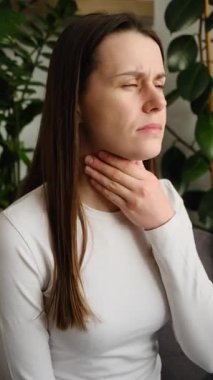 Sağlıksız bir hastalık genç beyaz kadın, kötü öksürüyor, soğuk, boğaz ağrısı var, kanepede tek başına oturuyor, kötü öksürük belirtilerinden muzdarip.