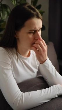 Endişeli, üzgün, genç bir kadın, evinde oturmuş, düşüncelere dalmış, endişeli, mutsuz esmer bir kadın, ruhsal psikolojik sorunlardan muzdarip.