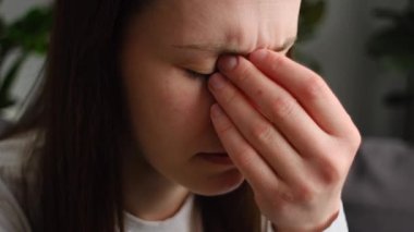 Güçlü göz ağrısından muzdarip üzgün kadına yaklaş. Görme sorunu. Oturma odasındaki kanepede oturan yorgun, genç bir bayan gözlerini okşuyor. Yaralanmalar Sağlık Hastalığı Konsepti