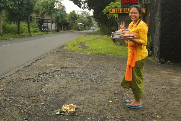 Balinese woman bring offerings of fruits and gifts to the village temple — Stok fotoğraf