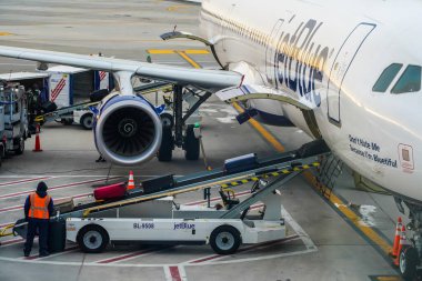 NEW YORK- 30 ARALIK 2020: JetBlue bagaj idarecisi New York 'taki John F. Kennedy Uluslararası Havaalanı' nda piste bagaj yüklüyor