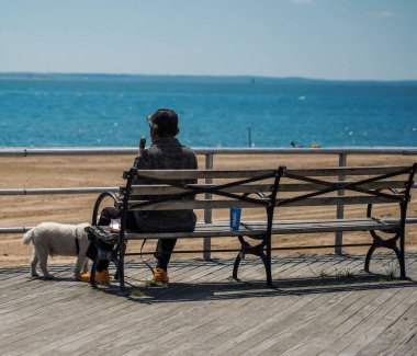BrooKLYN, New York - 11 Mayıs 2021: Köpekli tanımlanamayan adam Brooklyn, New York 'taki Coney Island Boardwalk' ta eğleniyor