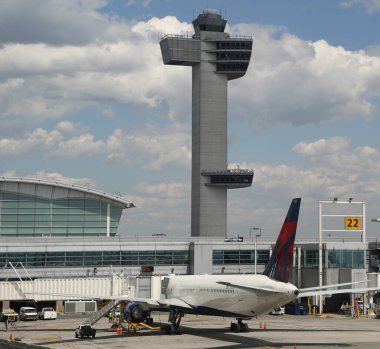 NEW YORK - 16 Mayıs 2019: Hava Trafik Kontrol Kulesi ve Delta Havayolları uçağı JFK Uluslararası Havaalanı 'ndaki Terminal 4' te pistte. JFK, 4 pisti ve 8 terminali olan dünyanın en büyük havaalanlarından biridir.