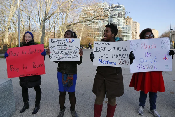 Un manifestante sostiene un letrero durante una marcha contra la brutalidad policial y la decisión del gran jurado sobre el caso Eric Garner en el Grand Army Plaza de Brooklyn —  Fotos de Stock