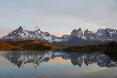 Cliffs of Los Kuernos reflection during sunrise at Lake Pehoe in National Park Torres del Paine