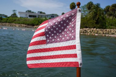 Sakin bir su kütlesinin üzerinde Amerikan bayrağı usulca dalgalanır