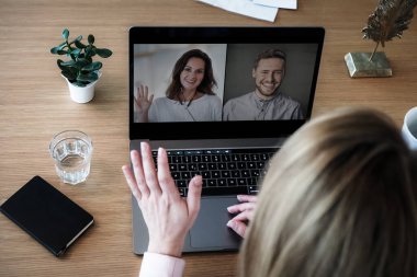 Bilgisayarında çalışan uzaktan kumandalı bir çalışan kadın bir toplantıda video konferansı ya da web sunumu izlemek için konuşurken, flört ederken ve el sallarken bilgisayarının başında.