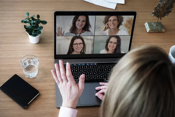 Bilgisayarında çalışan uzaktan kumandalı bir çalışan kadın bir toplantıda video konferansı ya da web sunumu izlemek için konuşurken, flört ederken ve el sallarken bilgisayarının başında.