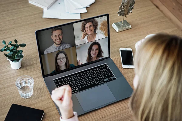 Uzaktan kumandalı online çalışan bir kadın iş masasında laptopuyla oturuyor ve bir online toplantıya katılıyor ya da video konferansı veya webinar sunumu izliyor.