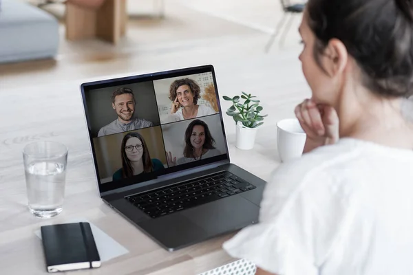 remote online working woman sitting on a work desk with laptop in in her home office joining an online meeting or watching video conference or webinar presentation