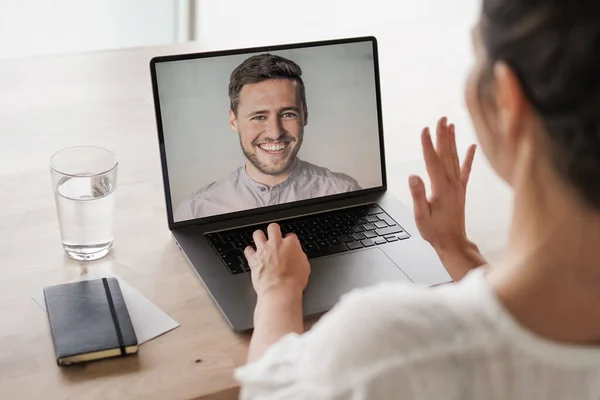 Bilgisayarında çalışan uzaktan kumandalı bir çalışan kadın bir toplantıda video konferansı ya da web sunumu izlemek için konuşurken, flört ederken ve el sallarken bilgisayarının başında.