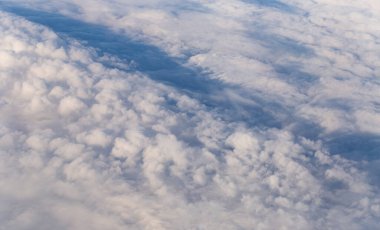 Stratosfer, bir uçak penceresinden bulutların görüntüsü. Gökyüzünde kümüliform bulutları. Arazinin üzerinde uçarken.