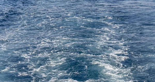 Turbulent flow of a boat wake. Sea wave. The yacht sails, leaving behind a trail and waves.