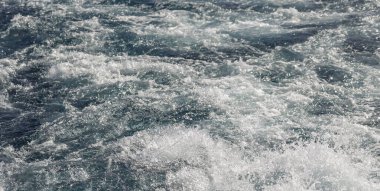 Dalgalı bir tekne dalgası. Deniz dalgası. Yat yelken açıyor, arkasında iz ve dalgalar bırakıyor..