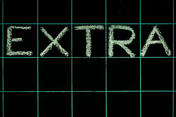 Extra word handwritten on black chalkboard — Stock Photo, Image