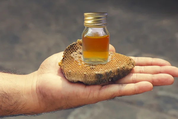Honeycomb och honung i flaska på mänsklig hand — Stockfoto