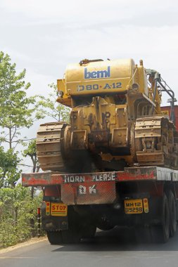 bulldozer loaded truck on road, india