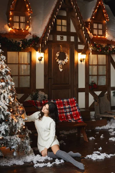 Une jeune femme en robe tricotée chaude décore un sapin de Noël pour les fêtes du Nouvel An — Photo