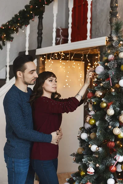 Beau couple romantique décorant l'arbre de Noël dans le salon intérieur pour les vacances de Noël — Photo