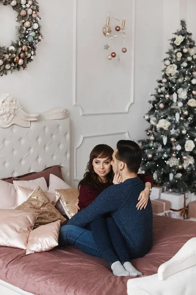 Doux couple étreignant sur le lit dans une chambre décorée pour les vacances de Noël — Photo