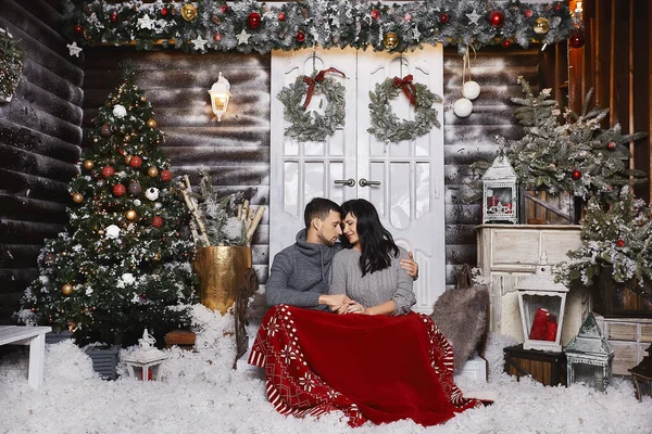 Bella coppia, elegante bell'uomo e giovane bruna in felpe grigie alla moda, che si abbracciano e posano all'interno decorati per Natale — Foto Stock