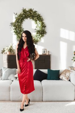 Oturma odasının üzerinde kırmızı gece elbisesi giymiş genç bir kadın Noel için dekore edilmiş. Mutlu Noeller ve mutlu yıllar.