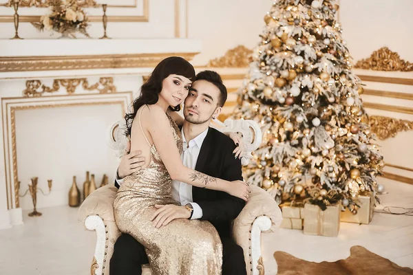 Великолепная молодая пара влюбленных в модных нарядах на роскошный интерьер, украшенный к Рождеству — стоковое фото
