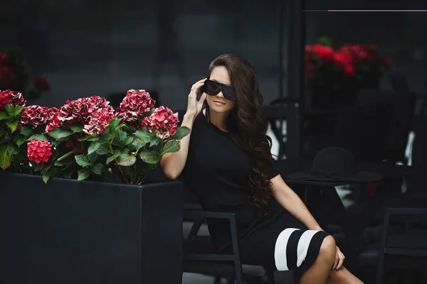 Krásná, módní brunetka modelka dívka v černých šatech pózuje venku, jaro — Stock fotografie