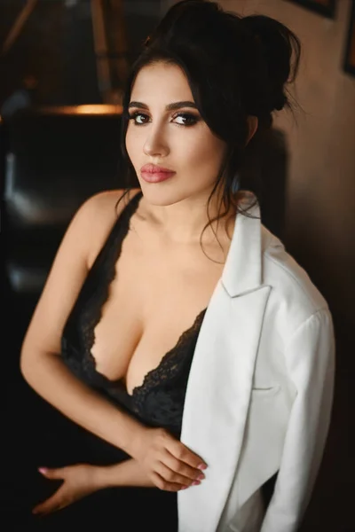 Porträt der sexy Latino-Frau mit großen Brüsten im schwarzen sexy Outfit, die in die Kamera blickt. Vollbusige Model-Frau mit hellem Make-up und vollen Lippen — Stockfoto
