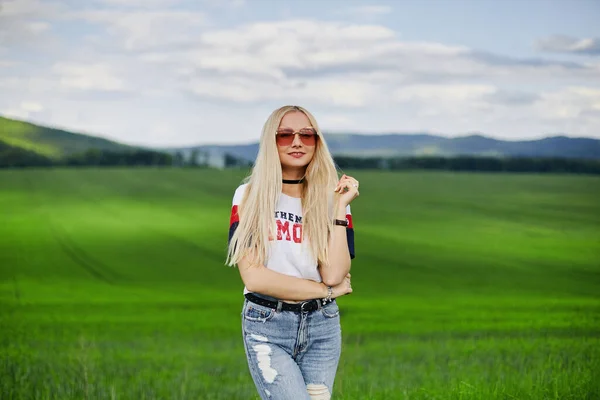 Jeune femme aux cheveux blonds portant un jean et un t-shirt posant à la campagne — Photo