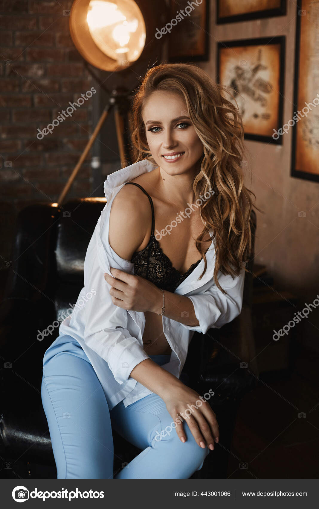 Model woman with sporty shaped body in an unbuttoned shirt and black bra  posing in the interior. Model girl with perfect body and make-up indoors  Stock Photo by ©innarevyako 443001066