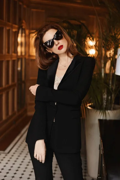 Mulher modelo jovem na moda em um terno preto elegante e óculos de sol pretos. Beleza, moda. Óptica e óculos — Fotografia de Stock