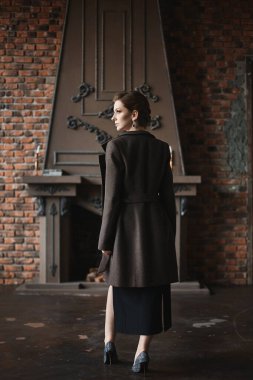 Şık ceketli, ince vücutlu, güzel model bir kadın klasik iç mekanda poz veriyor.