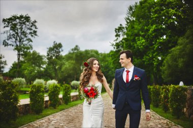 Düğün töreninden sonra parkta yürüyen mutlu, yeni evli bir çift. Düğün günlerinde. Mükemmel bir çift, gelin ve damat dışarıda poz veriyorlar.