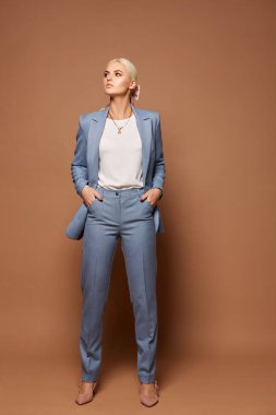 Modayı takip eden mavi takım elbiseli, beyaz bluzlu ve bej renkli ayakkabılı genç bir kadın. Arka planda fotokopi alanı var. İş modası ve güzellik kavramı