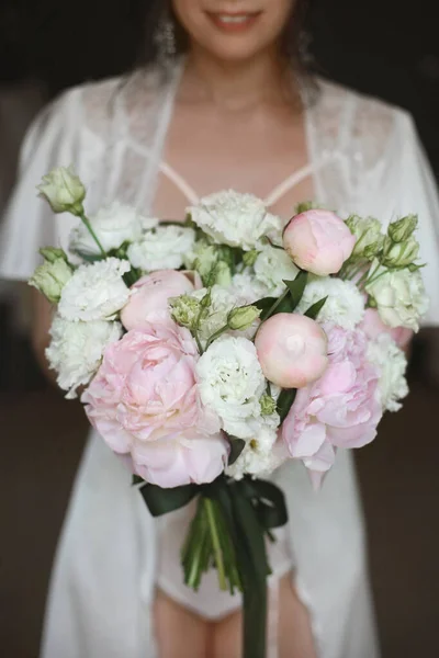 Brautstrauß aus weißen Rosen und Pfingstrosen in den Händen der jungen schönen Braut am Morgen vor der Trauung — Stockfoto