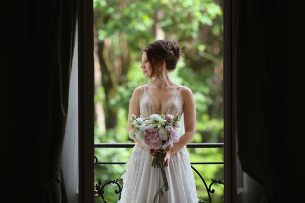 Sexy e bella ragazza modello in un abito da sposa in pizzo elegante e alla moda con spalle nude in posa in interni vintage di lusso — Foto Stock