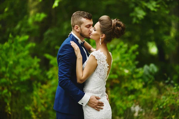 Möglig brudgum kysser vacker brud under bröllopsceremonin. Ett kärleksfullt par, en flicka i bröllopsklänning och stilig man i stilren blå kostym — Stockfoto