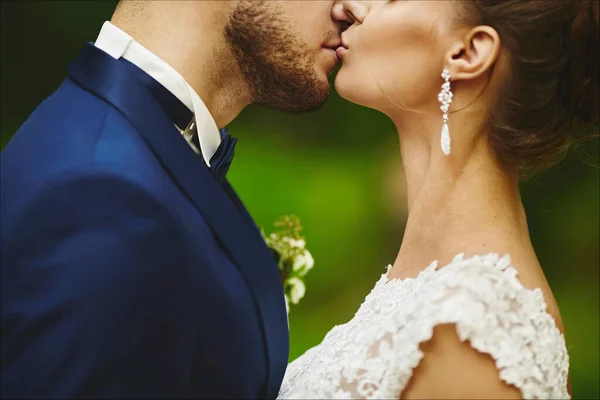Помірний наречений цілує розкішну наречену під час весільної церемонії. Любляча пара, дівчина у весільній сукні і красивий чоловік у стильному синьому костюмі — стокове фото