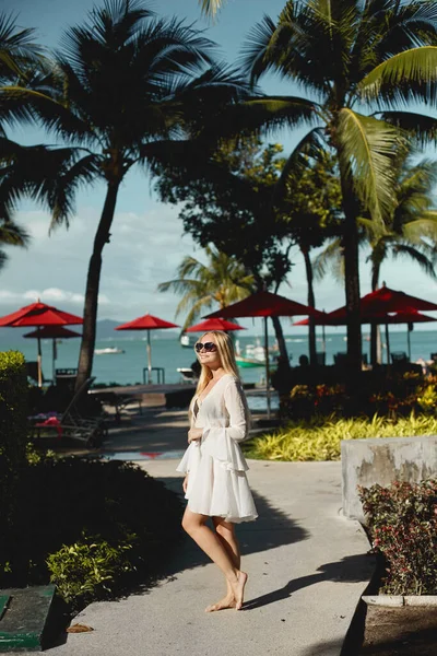 Glückliches Modelmädchen im Bikini posiert unter Palmen auf dem Gelände des luxuriösen Resorts auf der tropischen Insel — Stockfoto