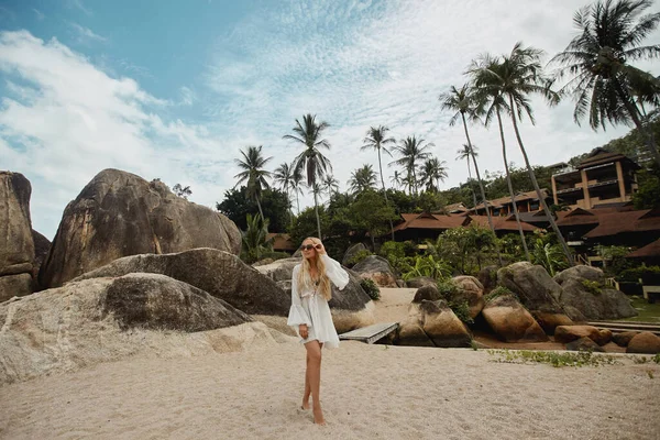 Tropische Inselreise der jungen Model-Frau, die am Strand posiert, mit einem exotischen Luxushotel im Hintergrund — Stockfoto